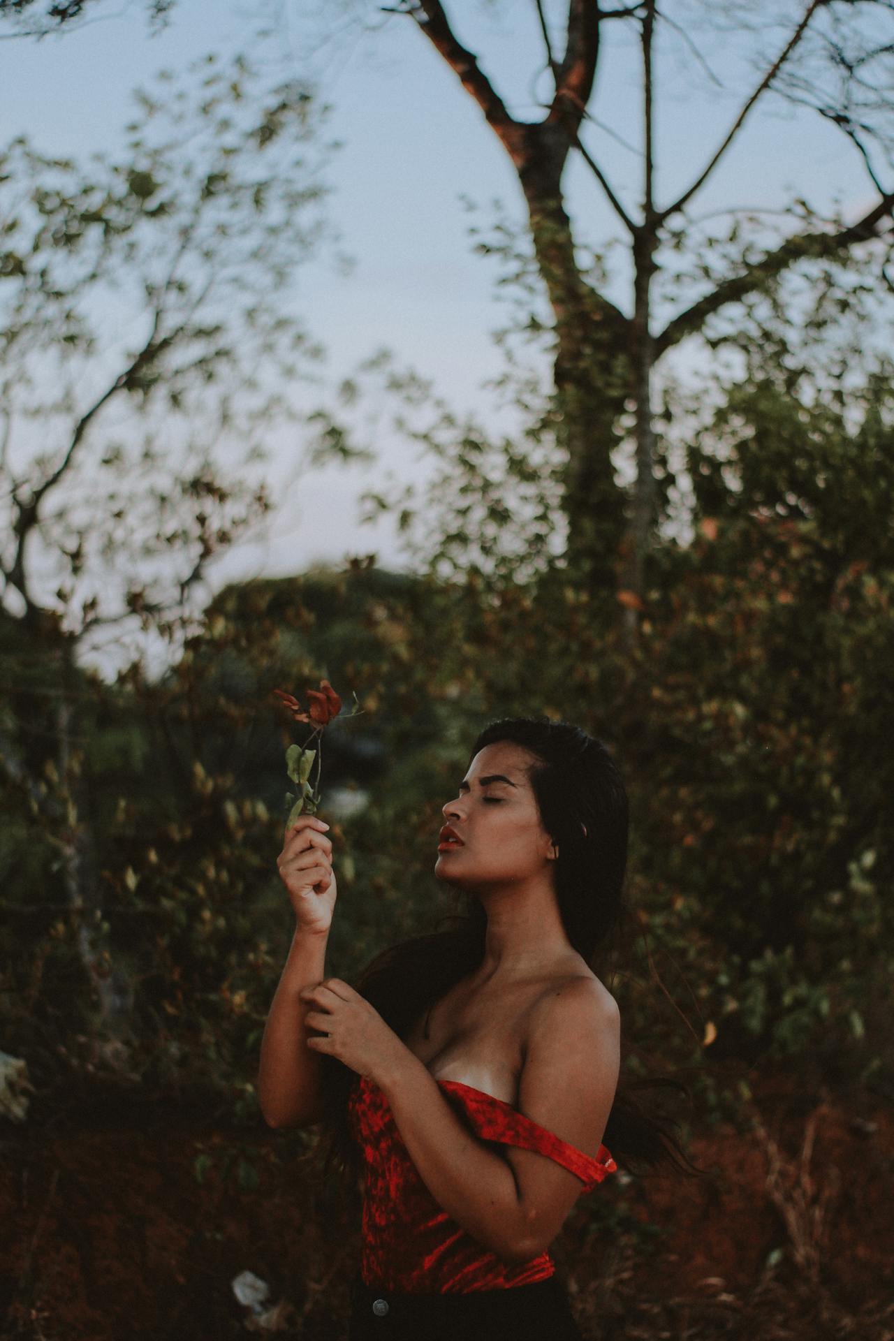 woman holding a flower posing for a photo